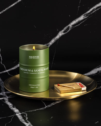 Green candle with 'M&SENSE' branding on a gold tray against a black background