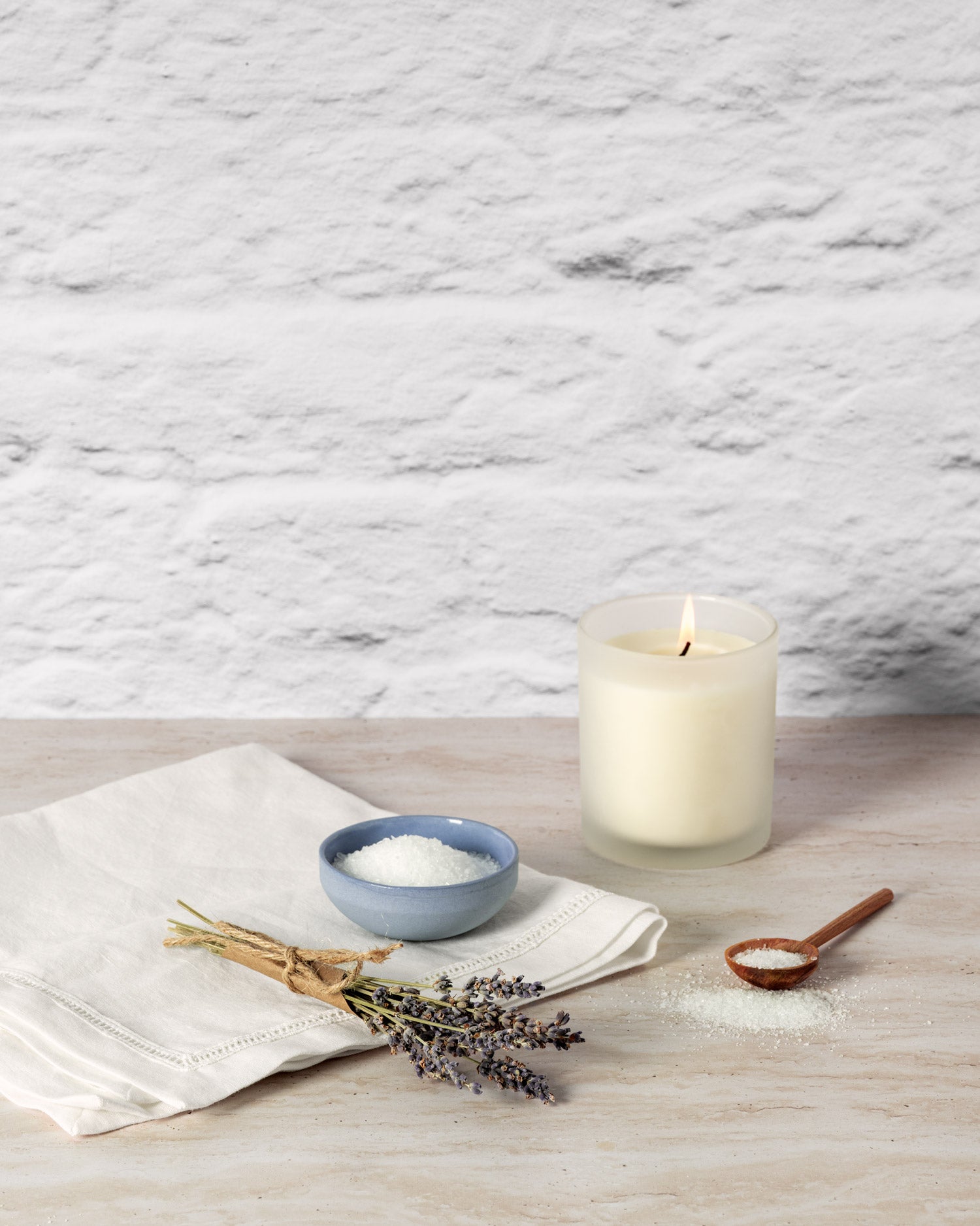 Candle, bowl of powder, and lavender on a marble surface